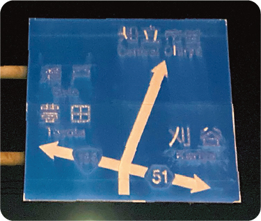 劣化して視認性に乏しくなった道路案内標識（夜間）
